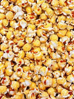 A close-up, top-down view of golden yellow and white popcorn kernels filling the entire frame of our Sweet Maui Onion flavored ready to eat popcorn.